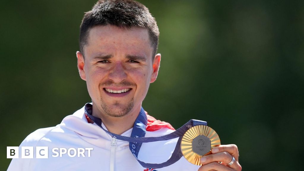 Tom Pidcock holding his Olympic gold medal